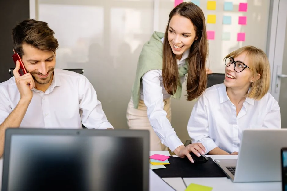 our-story Scène de bureau avec des collègues aux profils variés autour d’une femme stressée tenant une pancarte indiquant HELP. Mettre l’accent sur les dynamiques de travail en équipe.
