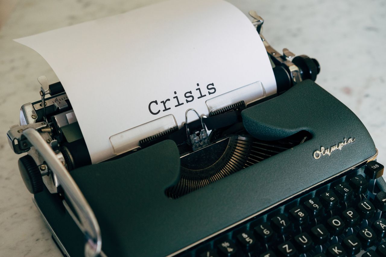 Gros plan sur une machine à écrire vintage avec le mot Crisis tapé sur le papier.